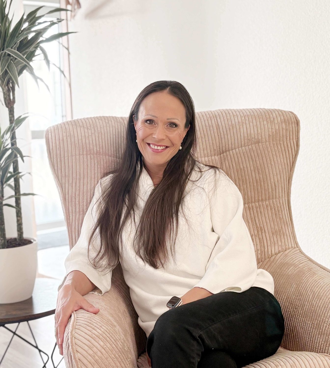 Porträt von Melanie Christl, psychologische Beraterin, sitzend in einem Sessel in ihrer Praxis in Seligenstadt